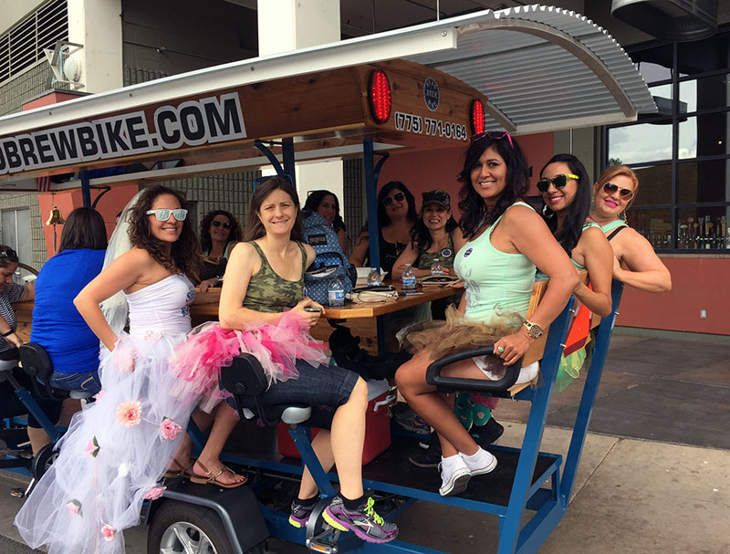 Woman in wedding dress with friends seated on the Brew Bike