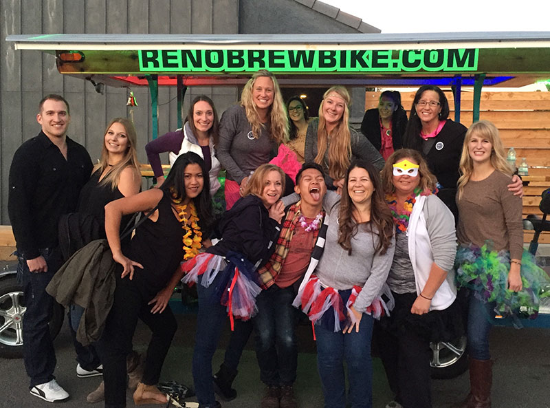 Group of women and men smiling in celebration in front of the Brew Bike