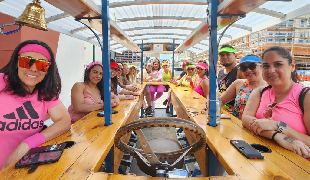 A 15 passenger birthday party, all wearing pink, sitting in Brew Bike seats